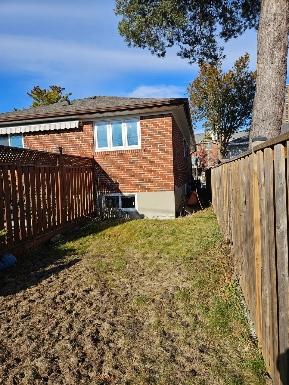 Before: the original white-framed window in the brick rear wall, with a basement window below and no direct access to the backyard.