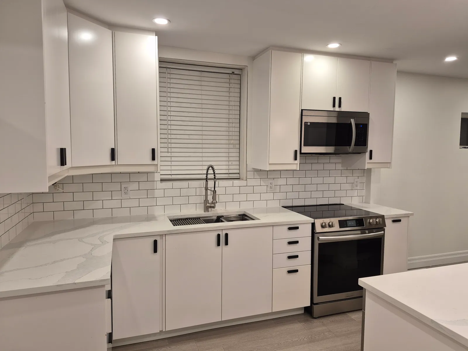 Finished kitchen cabinetry, countertop and tiled backsplash around the sink and range.
