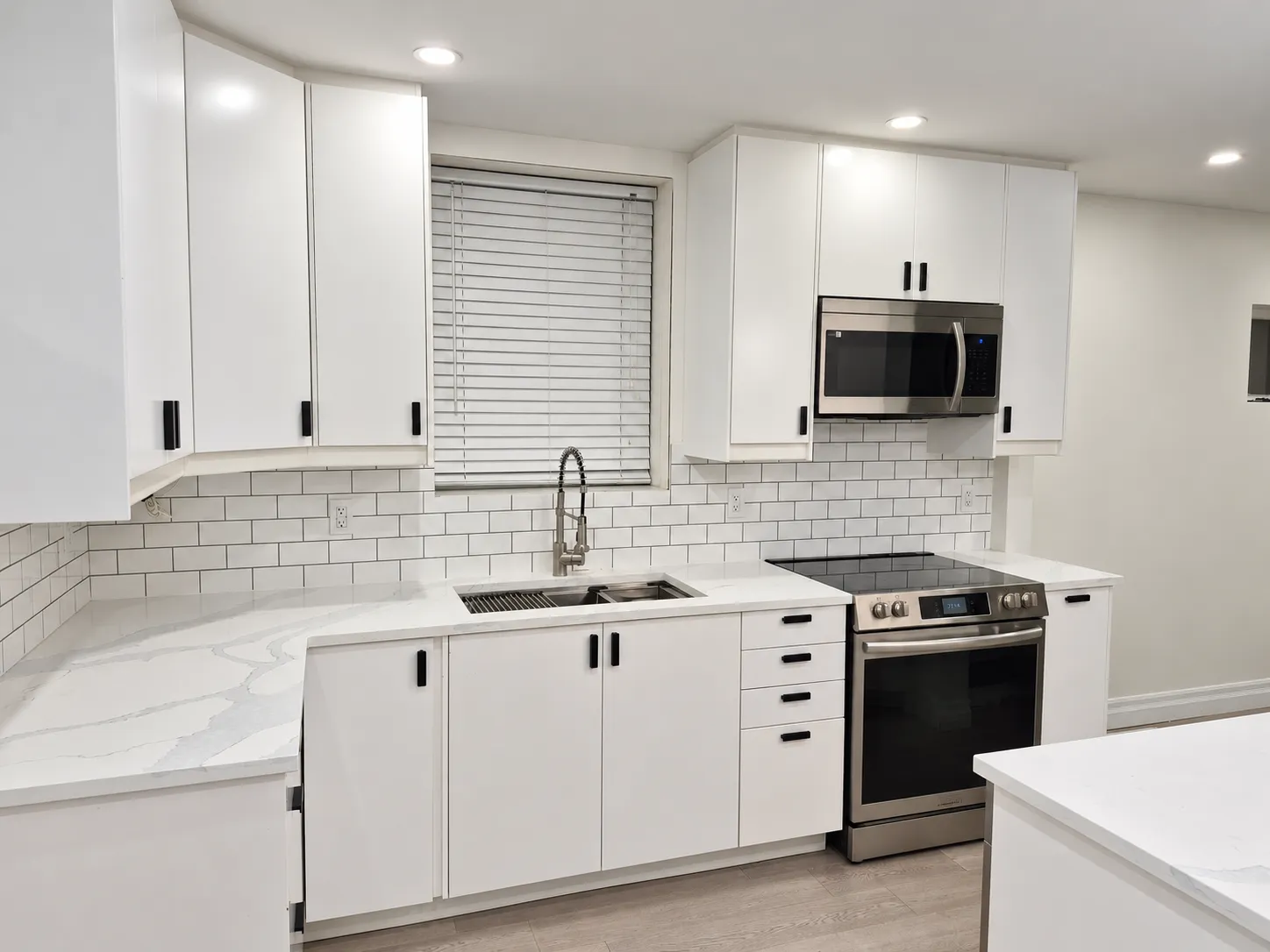 Kitchen with white cabinets, marble-look counters, subway-tile backsplash and stainless appliances.